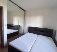 Bedroom in a 3-room apartment with a double bed, mirrored wardrobe, and wooden decor flooring.