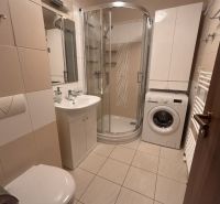 Bathroom in a 3-room apartment with a bathtub, washing machine, and storage space.