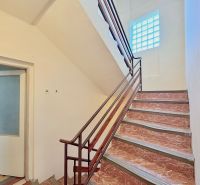 A staircase in a family house with a glass block window and open doors.