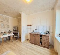 A kitchen in a family house with a wooden decor floor and a dining table.