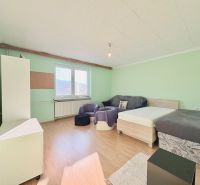 A room with beds, a sofa, and a wooden decor floor in a family house.