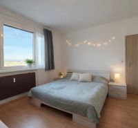 Bedroom in a 4-room apartment with a bed, curtains, and a wooden decor floor.
