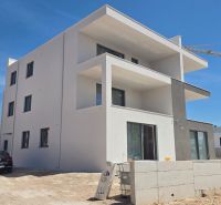 A newly built three-story apartment building in the town of Srima under a blue sky.