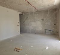 An unfinished room in a 3-room apartment with wires hanging from the ceiling.