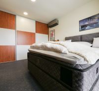 A bedroom in a family house with a large bed and a sliding wardrobe.