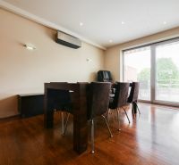 Dining room in a family house with a wood-patterned floor and glass doors to the terrace.