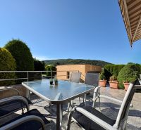 In Partizánske, a terrace of a family house with garden furniture and a view of greenery.