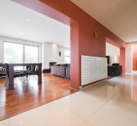 Living room in a family house with wood-patterned flooring and a dining table.