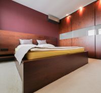 Bedroom in a family house with a bed, built-in wardrobe, and a burgundy wall.