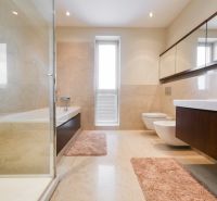 Bathroom in a family house with a bathtub, sink, and mirrored cabinets.