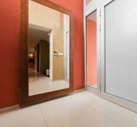 The interior of a family house with a large mirror, white doors, and beige tiles.