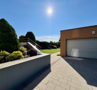 The exterior of a family house in Partizánske with a garden and a garage under sunny weather.