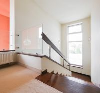 A staircase with modern railing and carpet in a family house, sunny room.