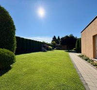 The garden of a family house in Partizánske with a well-maintained lawn and a paved walkway.