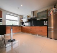 A kitchen in a family house with a chrome refrigerator and a wooden decor floor.