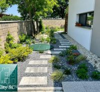 Garden path in a family house in Senec surrounded by plants and stones.