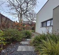 A family house in Senec with a landscaped garden path, decorated with pebbles and green plants.