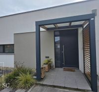 A family house in Senec with a minimalist facade, entrance doors, and a pergola.