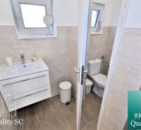 Bathroom with a sink, toilet, and wood-patterned floor in a family house.