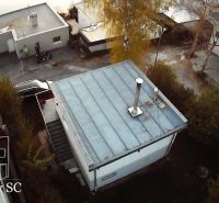 Cottage in Senec at SUNNY LAKES SOUTH, with a flat roof, surrounding trees, and a road.