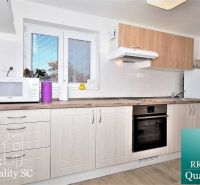A kitchen in a cottage with a microwave, oven, and wood-patterned flooring.