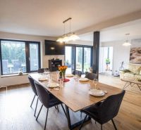 Dining table and sofa with wood-patterned flooring in a family house.