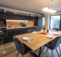 A kitchen in a family house with a large dining table and a floor with a wooden decor.