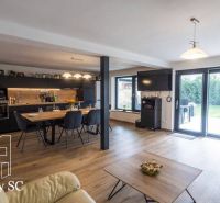 Interior of a family house with wide windows, a kitchenette, and a wooden decor floor.