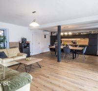 Family house living room with kitchen, wooden decor flooring, comfortable seating.