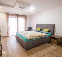 A bedroom in a family house with a wood-decor floor and minimalist furnishings.