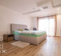 Bedroom with a bed, dresser, nightstands, and wooden decor flooring in a family house.