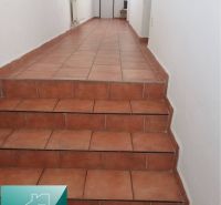 A hallway with ceramic tiles and a staircase in a family house.