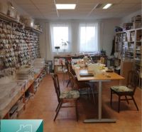 A room in a family house with shelves for materials and a long workbench.