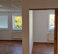 Interior of a family house with terracotta flooring, white walls, and radiators under the windows.