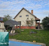 A family house in Turany with a lawn, a gazebo, and an outdoor fireplace in the garden.