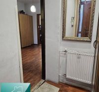 A space in a family house with a wooden decor floor, a mirror, and a radiator.