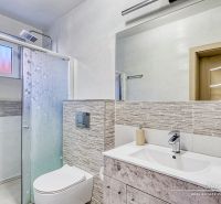 A compact bathroom with a toilet and a shower in a family house, decorated with mosaic tiles.