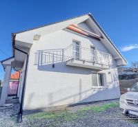 A family house in Hrnčiarovce nad Parnou with a white facade and a balcony on a gravel yard.