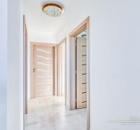A hallway in a family house with tiles, wooden doors, and stylish lighting.