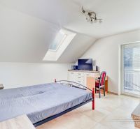 An attic bedroom in a family house with simple furniture and a skylight.