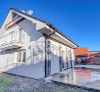 A family house in Hrnčiarovce nad Parnou with a concrete terrace and a balcony on the upper floor.