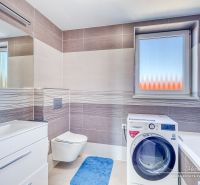 A bathroom in a family house with a washing machine, a sink, and a window with frosted glass.