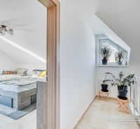 Attic bedroom with a bed and a window, plants on the staircase, family house.