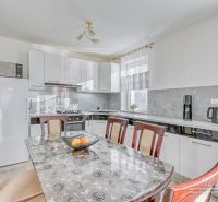 A kitchen in a family house with white cabinets, a table, and appliances.