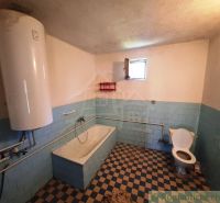 Bathroom in a family house with a bathtub and a water heater.
