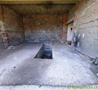 An unfinished garage in a family house with a service pit. Walls made of unplastered brick.