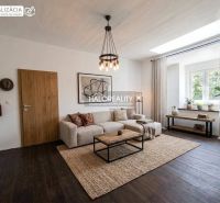 Living room of a three-room apartment with a wooden decor floor and a large window.