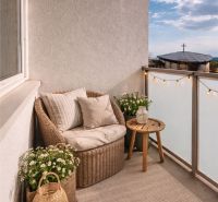A balcony of a 4-room apartment with rattan furniture and decorations in a pleasant style.