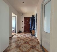 A hallway with ceramic tiles in a 4-room apartment with two doors and a coat rack on the wall.
