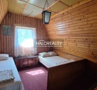 A wooden room with two beds in a cottage. Dim lighting and carpets.